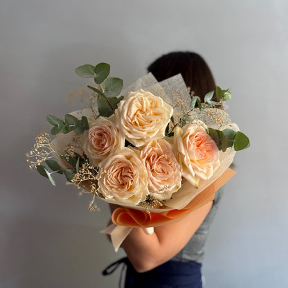 Bouquet of roses held by a person against a plain background