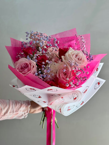 Bouquet of pink roses with pink wrapping paper held by a person against a gray background