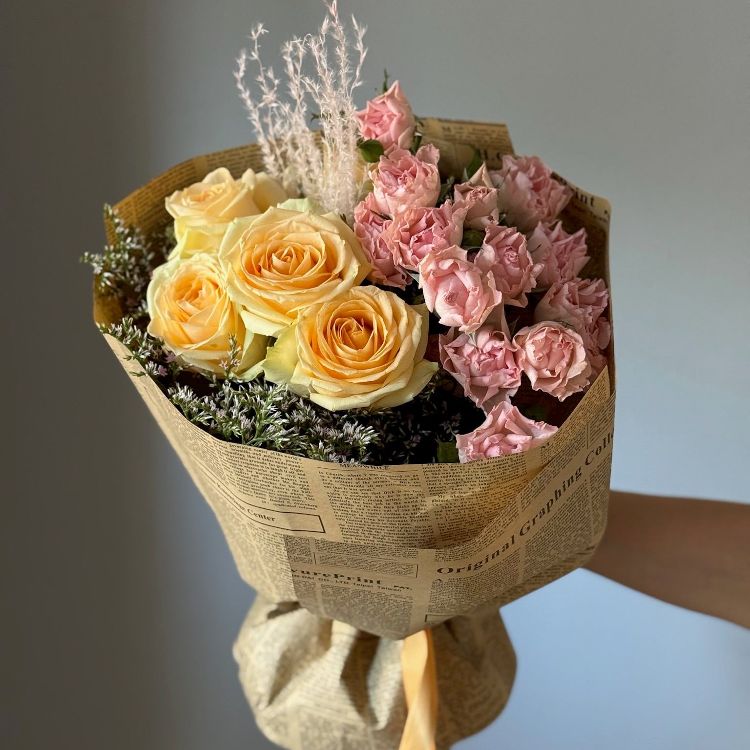 Yellow and pink flowers in newspaper wrapping paper in bouquet