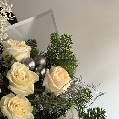 Bouquet of white roses with greenery and silver ornaments on a light background