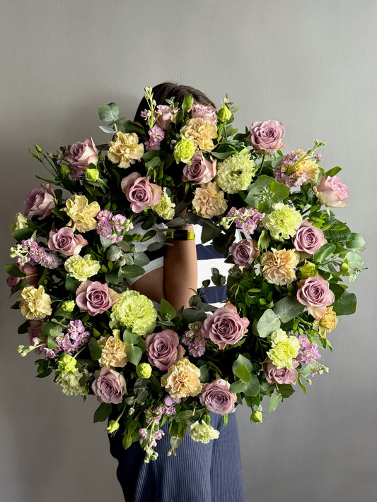 Floral wreath held by a person against a gray background