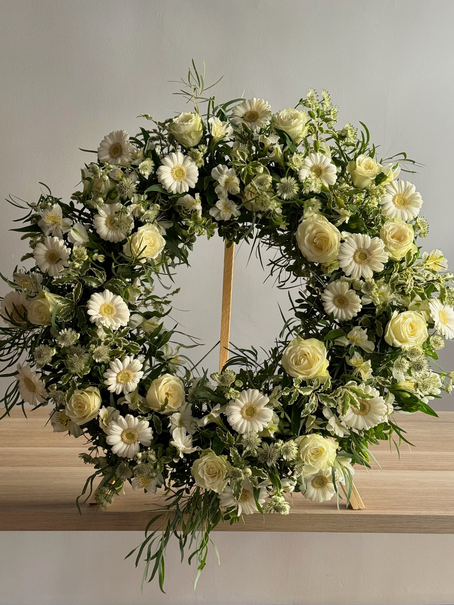 Floral wreath with white and yellow flowers on a wooden surface