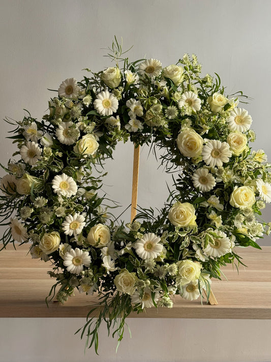 Floral wreath with white and yellow flowers on a wooden surface