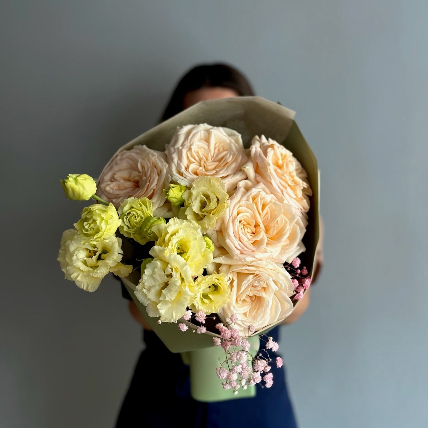Bouquet of flowers held by a person against a plain background