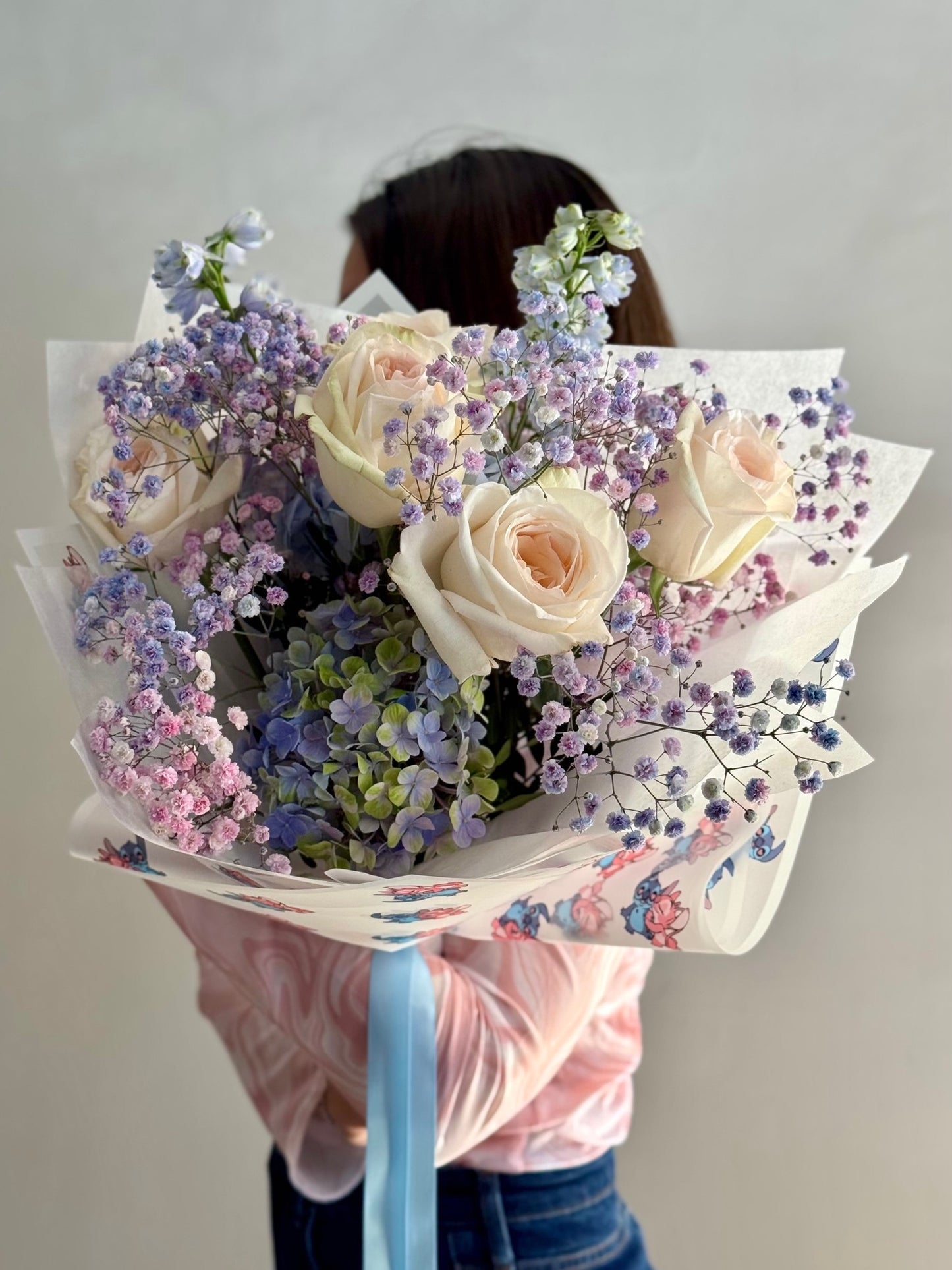 Bouquet of flowers held by a person against a plain background