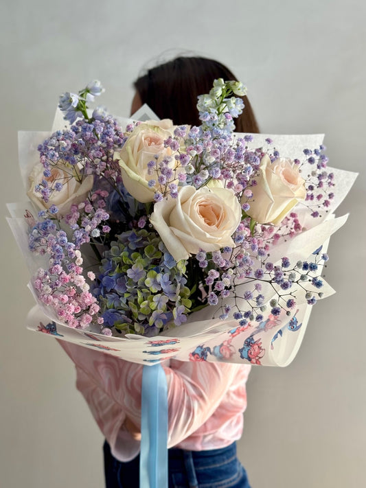 Bouquet of flowers held by a person against a plain background
