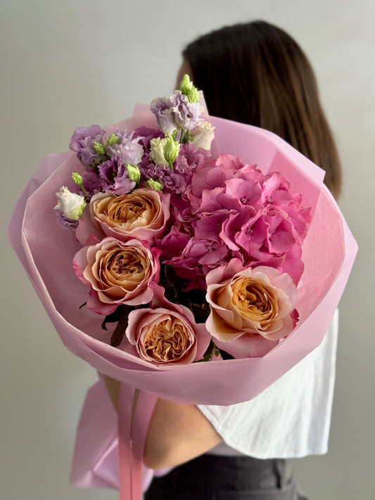 Bouquet of flowers held by a person with a plain background