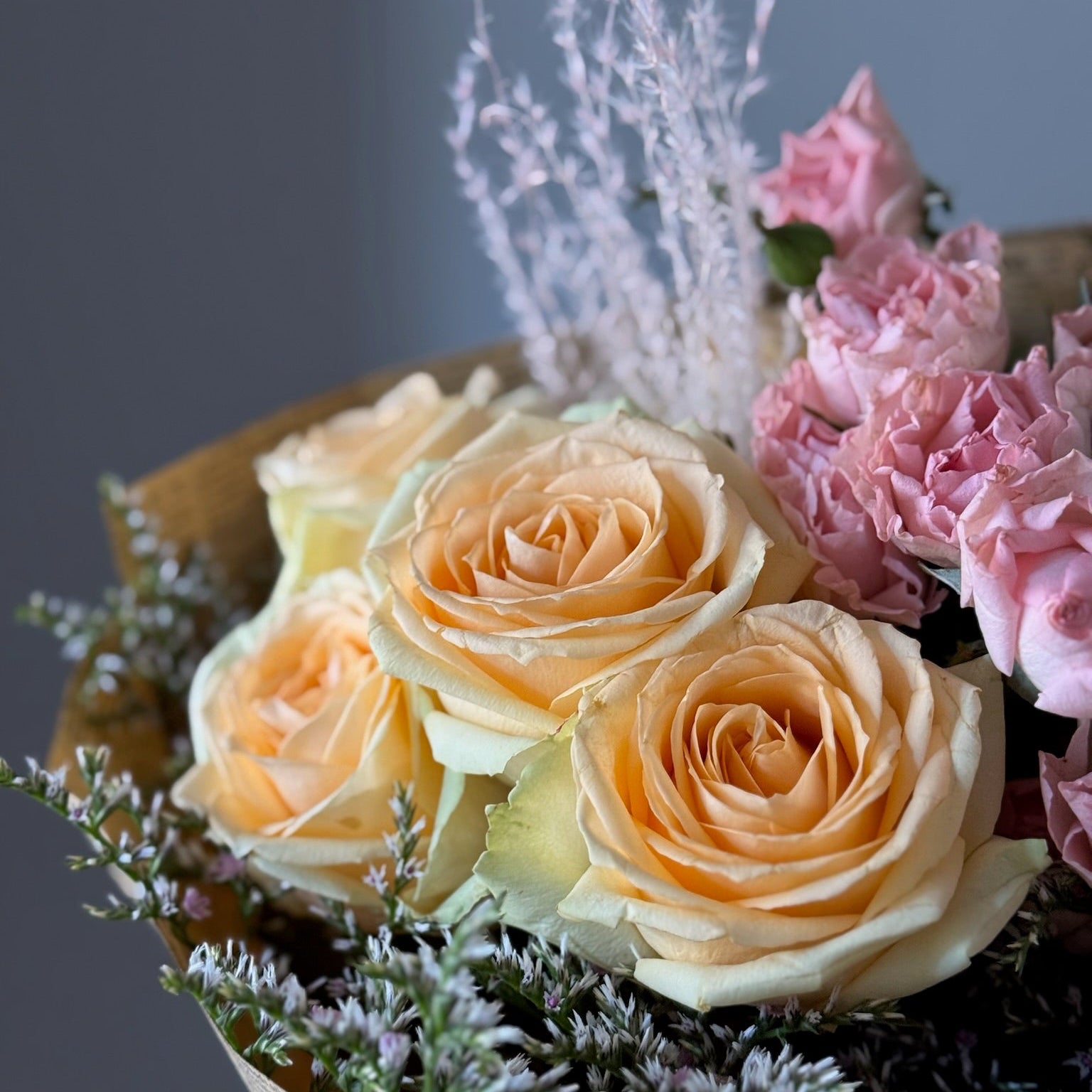 Yellow and peach roses on grey background 